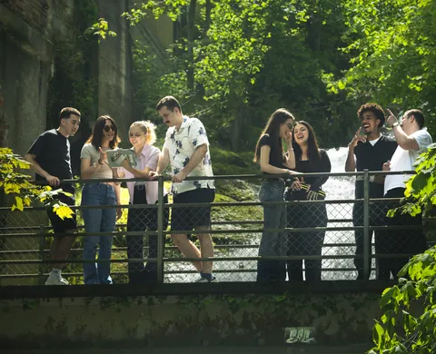 Eight players with a tablet on the bridge over the brook