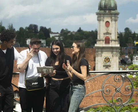 Four agents with a tablet above the rooftops, the cathedral behind