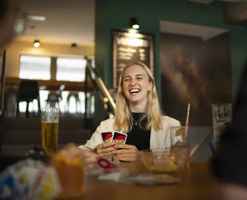Spielerin lacht mit den Karten in der Hand