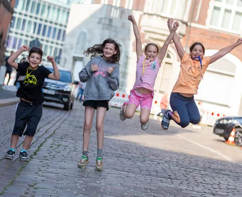 Four children jumping for joy in the street