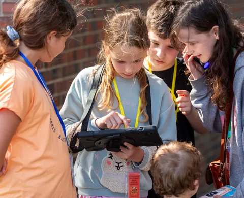Kinder-Forscherteam liest die Hinweise auf dem Tablet