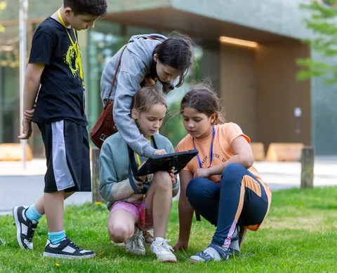 Young explorers kneeling in the grass with the tablet
