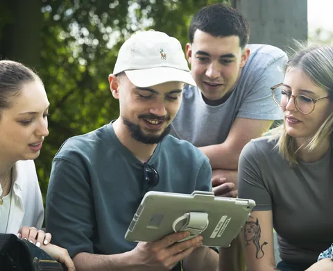 Four players with the tablet under the trees