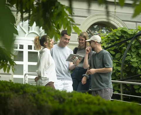 Team with the tablet at the railing in front of the palace