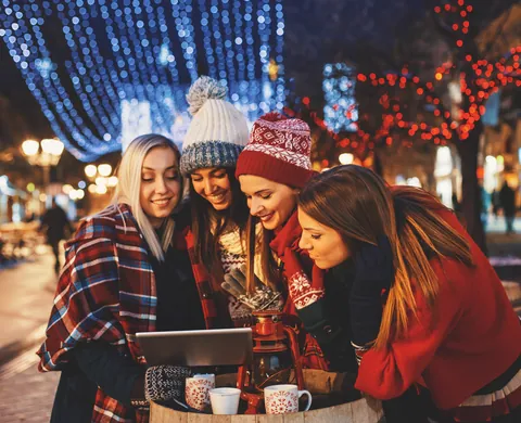 Team studiert das Tablet am Stehtisch im Lichterglanz