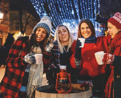 Gruppe mit Heissgetränken und roter Laterne unter den Weihnachtslichtern