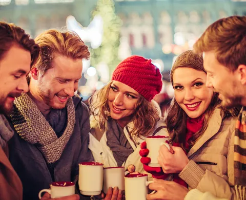 Freunde wärmen sich mit Punsch auf dem Weihnachtsmarkt