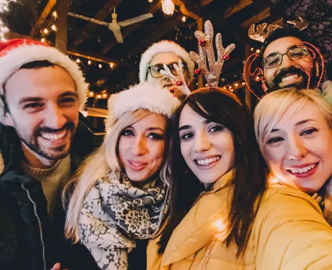 Team mit Weihnachtsmützen und Rentiergeweih beim Selfie