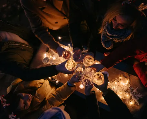 Anstossen mit Glühwein über der Lichterkette, von oben