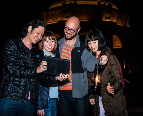 Team mit Tablet und Laterne vor der Kulisse bei Nacht