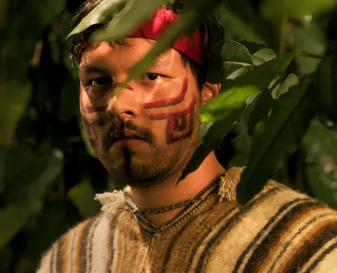 Maya warrior with face paint among the leaves