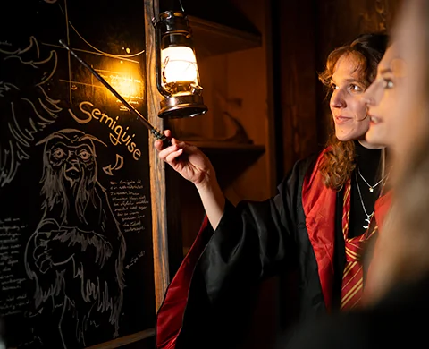 Spielerin mit Laterne vor Zaubertafel im World of Magic Escape Room
